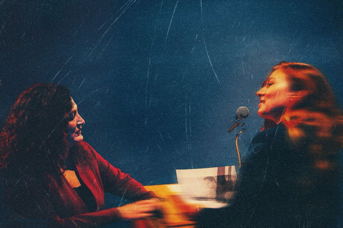 Kathryn Kellner coaching a speaker across the table at a microphone
